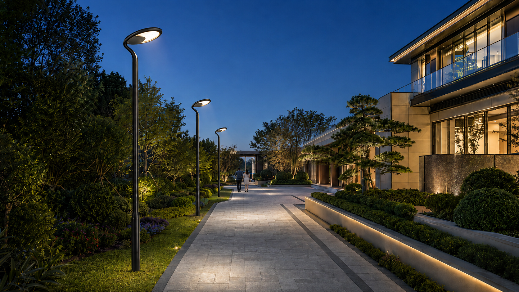 Array of commercial solar post-top lights illuminating a paved park avenue and pedestrian greenway corridor at dusk.